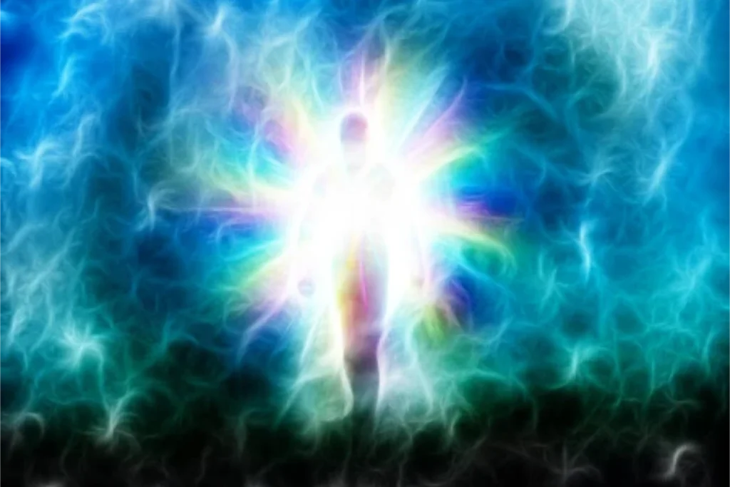 A glowing human silhouette radiates rainbow-colored energy, surrounded by swirling blue and white light patterns, symbolizing quantum energy healing or aura transformation.